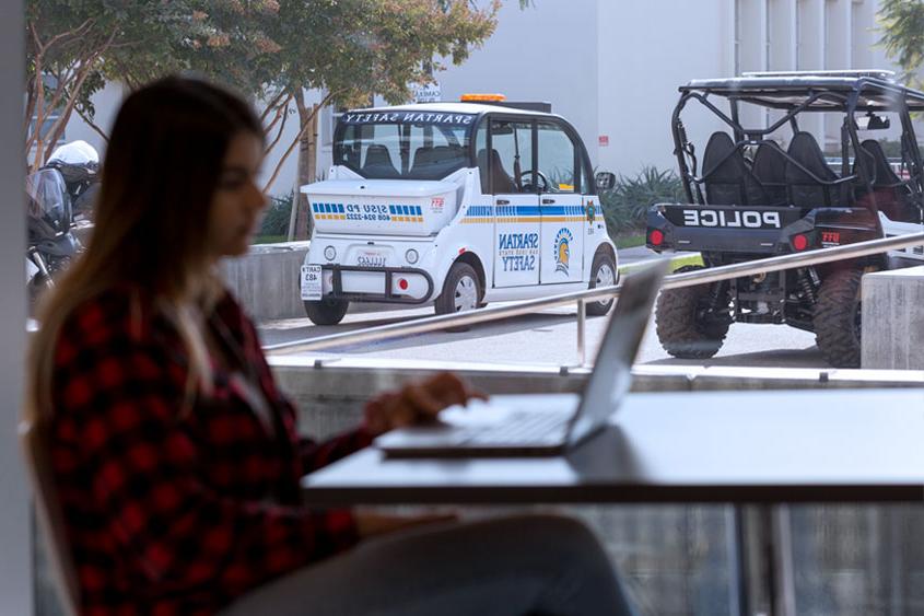 Student studying with police vehicles in background.
